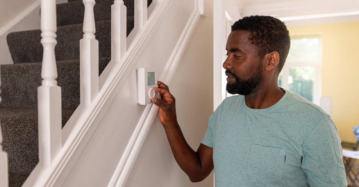 A man adjusts the thermostat in his apartment