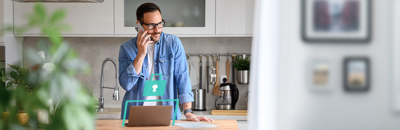 Man on his phone in kitchen with laptop